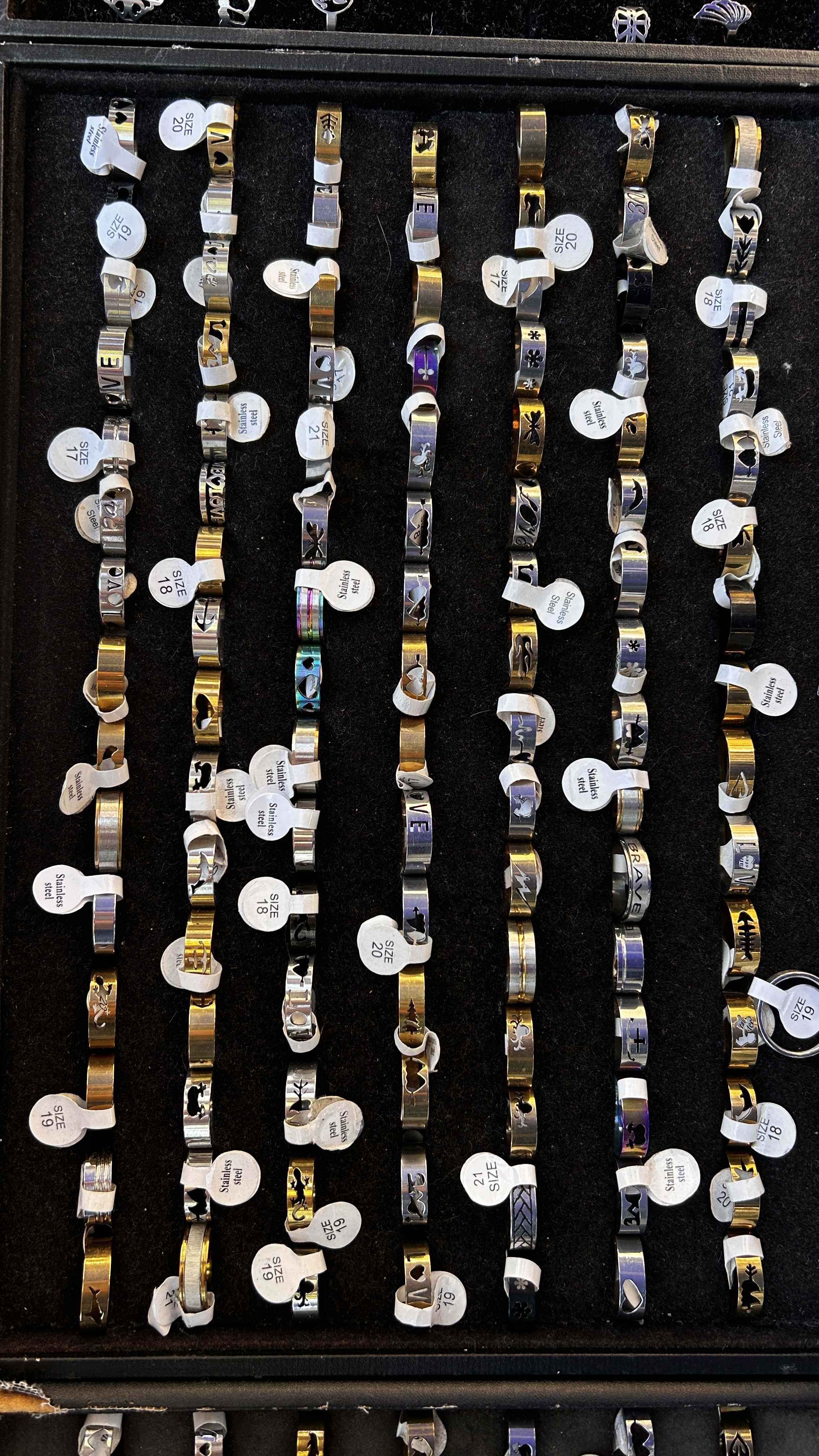 Rows of patterned stainless-steel rings in gold and silver tones.