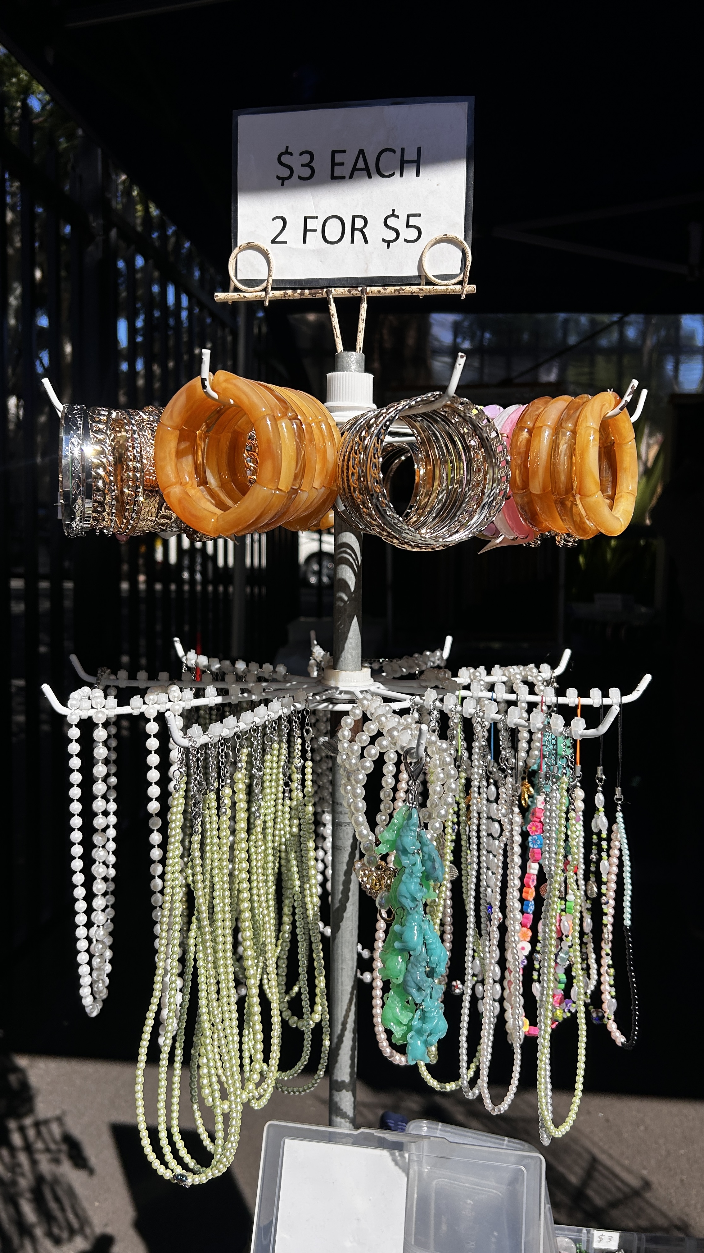 Pearl and colourful beaded necklaces displayed beneath a market sign.