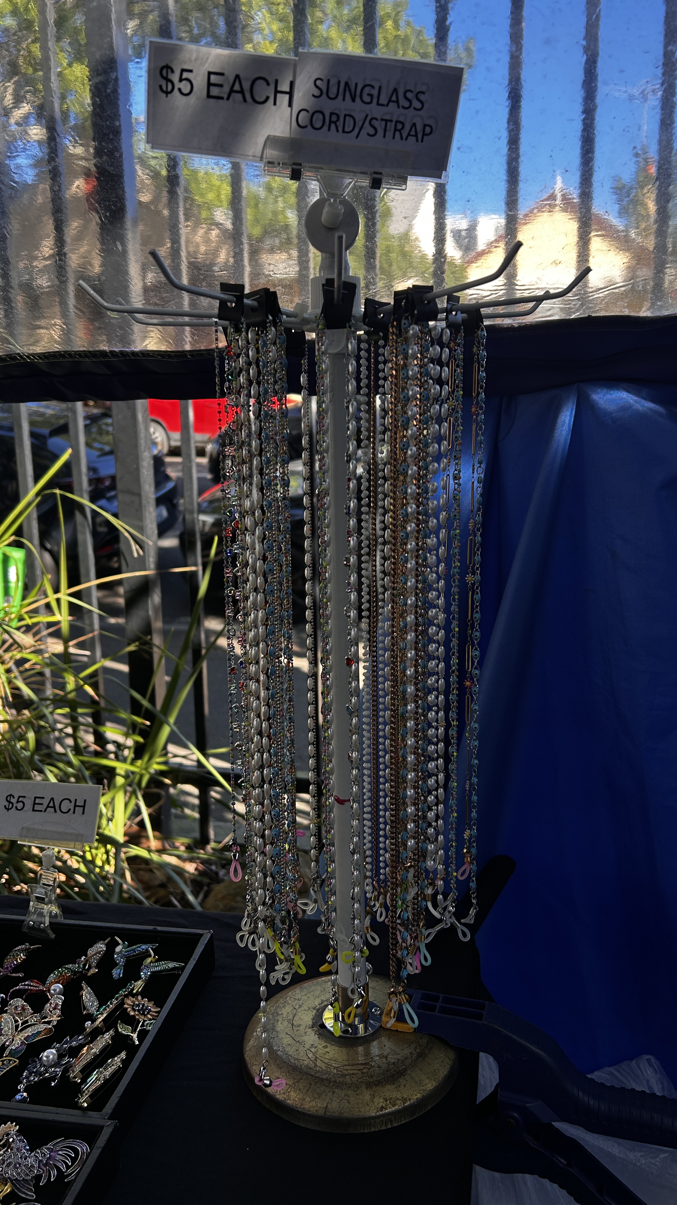 Beaded sunglass cords and straps hanging from a market display.